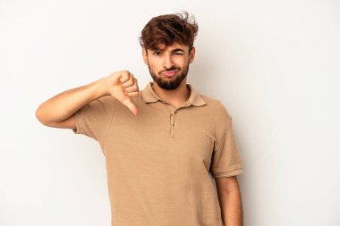 Genç melez adam gri arka planda izole edilmiş baş parmağını aşağı gösteren, hayal kırıklığı konsepti.