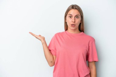 Mavi arka planda izole edilmiş genç beyaz kadın, avuç içinin fotokopi alanını tutmaktan etkilenmiş..