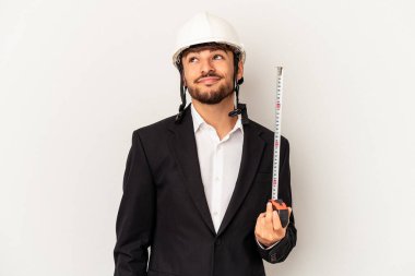 Miğfer takan ve taksimetre tutan genç bir mimar gri arka planda hedeflere ve amaçlara ulaşmayı hayal ediyor.