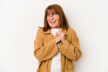 Beyaz arka planda izole edilmiş orta yaşlı beyaz bir kadın şans için dua ediyor, şaşırıyor ve ağzını açıyor..