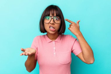 Mavi arka planda izole edilmiş genç melez kadın işaret parmağıyla bir hayal kırıklığı gösteriyor..