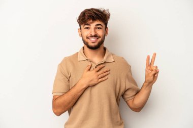 Genç melez adam gri arka planda izole edilmiş yemin ediyor, elini göğsüne koyuyor..