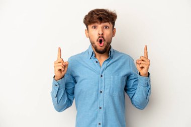 Genç melez adam, gri arka planda izole edilmiş, ağzı açık, üst tarafı işaret ediyor..
