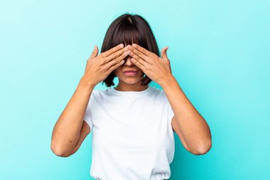 Mavi arka planda soyutlanmış genç melez bir kadın elleriyle gözlerini kapatmaktan korkuyor..