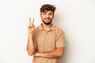 Genç melez adam gri arka planda izole edilmiş. İki numarayı parmaklarıyla gösteriyor..