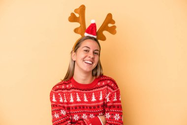 Sarı arka planda izole edilmiş Noel geyiği şapkası takan beyaz bir kadın gülüyor ve eğleniyor..