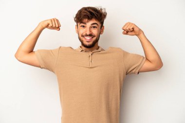 Gri arka planda izole edilmiş genç melez kadın gücünün sembolü olan kollarla güçlü bir hareket gösteriyor.