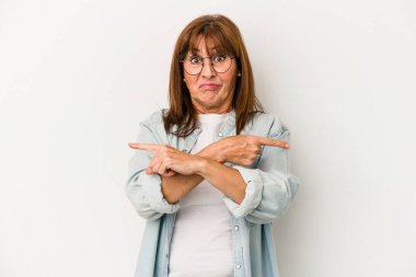 Beyaz arka planda izole edilmiş orta yaşlı beyaz kadın iki seçenek arasında seçim yapmaya çalışıyor..