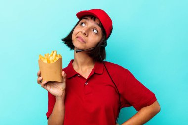 Genç melez ırk fast food restoranı çalışanı elinde kızartmalarla mavi arka planda hedeflerine ve amaçlarına ulaşma hayali kuruyor.