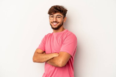 Genç melez adam gri arka planda izole edilmiş kendinden emin, kararlılıkla kollarını kavuşturuyor..