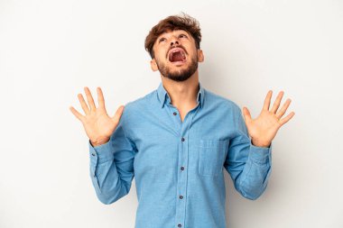 Genç melez adam gri arka planda izole edilmiş gökyüzüne haykırıyor, yukarı bakıyor ve hayal kırıklığına uğruyor..