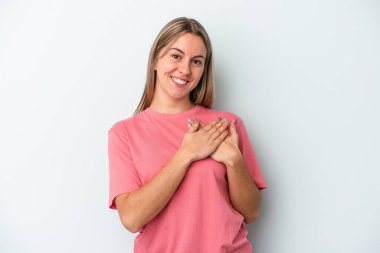 Mavi arka planda izole edilmiş beyaz bir kadın, dost canlısı bir ifadeye sahip, avuçlarını göğsüne bastırıyor. Aşk konsepti.