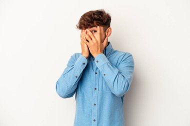 Genç melez adam gri arka planda izole edilmiş. Korkmuş ve gergin parmaklarıyla göz kırp..