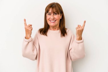 Beyaz arka planda izole edilmiş orta yaşlı beyaz kadın iki parmağı da boş bir alan gösteriyor..