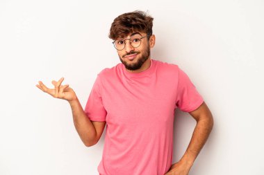 Genç melez adam, gri arka planda izole edilmiş şüpheli ve sorgulama sırasında omuz silkiyor..