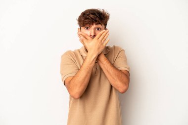 Gri arka planda yaşayan genç melez adam elleri ile ağzını kapatırken şok oldu..