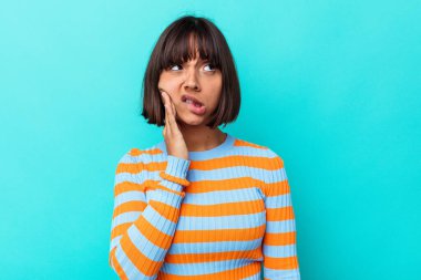 Mavi arka planda izole edilmiş genç bir ırk kadını. Güçlü bir diş ağrısı, azı dişi ağrısı var..