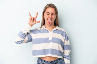 Mavi arka planda izole edilmiş genç beyaz kadın parmaklarıyla taş hareketi gösteriyor.