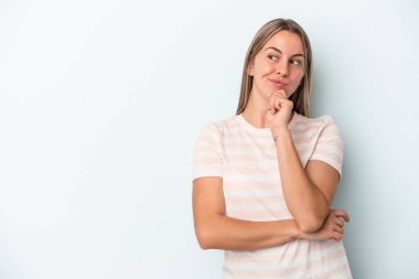 Mavi arka planda izole edilmiş genç beyaz kadın rahatça fotokopi odasına bakan bir şey düşünüyor..