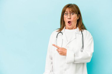 Middle age doctor woman isolated on pink background pointing to the side