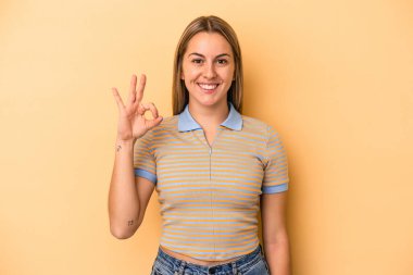 Sarı arka planda izole edilmiş genç beyaz kadın neşeli ve kendinden emin, iyi bir hareket gösteriyor..