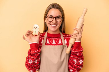 Sarı arka planda, Noel için kurabiye yapan genç fırıncı kadın.
