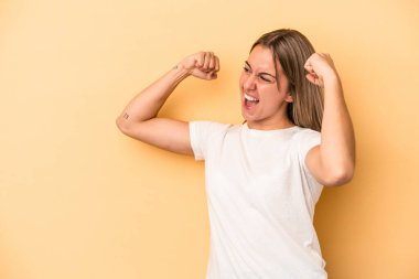 Sarı arka planda izole edilmiş genç beyaz kadın zaferden sonra yumruğunu kaldırıyor, kazanan konsept..