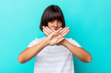 Mavi arka planda izole edilmiş genç melez bir kadın inkar hareketi yapıyor.