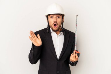 Miğfer takan ve taksimetre tutan genç mimar gri arka planda şaşırmış ve şok olmuştu..