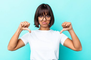 Mavi arka planda izole edilmiş genç melez bir kadın hoşlanmadığı bir jest gösteriyor. Anlaşmazlık konsepti.