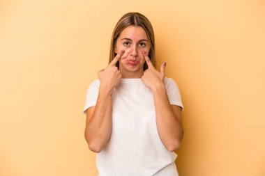 Sarı arka planda izole edilmiş genç beyaz kadın ağlıyor, bir şeyden memnun değil, acı ve kafa karışıklığı konsepti..