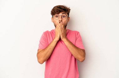 Gri arka planda yaşayan genç melez adam elleri ile ağzını kapatırken şok oldu..