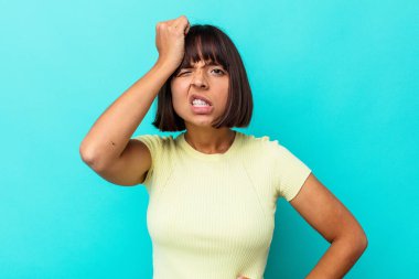 Mavi arka planda izole edilmiş genç bir ırk kadını bir şeyi unutuyor, alnına avuç içi ile vuruyor ve gözlerini kapıyor..