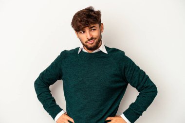 Genç melez adam gri arka planda izole edilmiş, kafası karışmış, şüpheli ve güvensiz hissediyor..