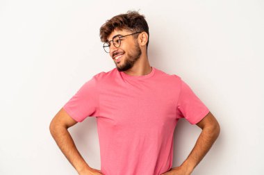 Genç melez adam, gri arka planda izole edilmiş. Kendine güvenen, ellerini kalçasında tutan..