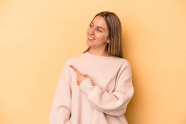 Sarı arka planda izole edilmiş genç beyaz kadın gülümseyen, neşeli ve hoş bakışlar atıyor..