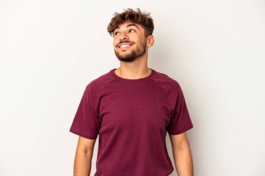 Genç melez adam gri arka planda izole edilmiş rahat ve mutlu bir şekilde gülüyor, boynunda dişlerini gösteriyor..