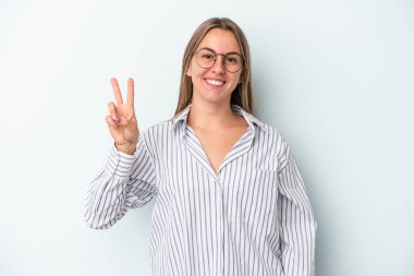 Mavi arka planda izole edilmiş genç beyaz kadın neşeli ve kaygısız parmakları olan bir barış sembolü gösteriyor..