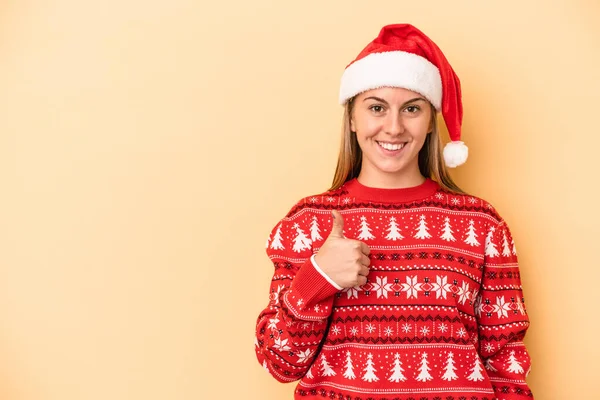 年轻的高加索女人在黄色背景下孤独地庆祝圣诞节 微笑着举起大拇指 — 图库照片