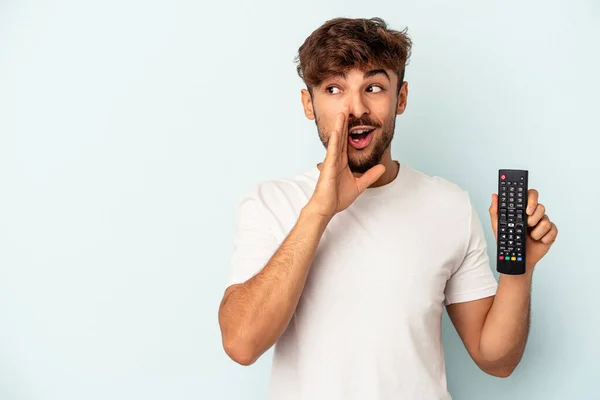 Jovem Mestiço Segurando Controlador Isolado Fundo Azul Está Dizendo Segredo — Fotografia de Stock