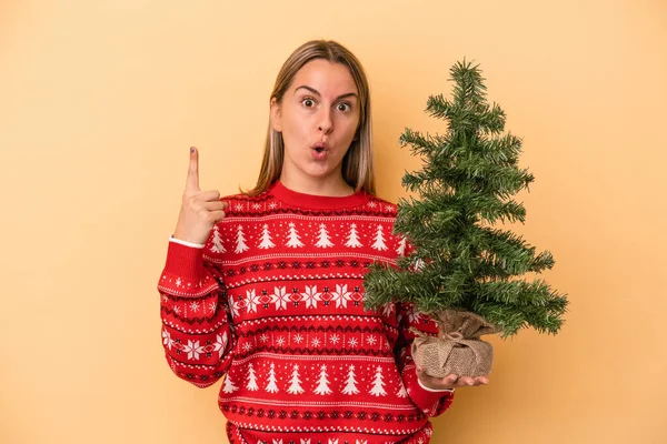 Mladá Běloška Drží Malý Vánoční Stromek Izolované Žlutém Pozadí Nějakou — Stock fotografie