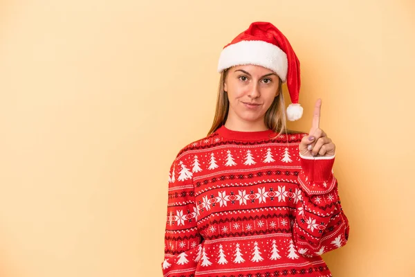 年轻的高加索女人用手指在黄色背景下庆祝圣诞节 — 图库照片