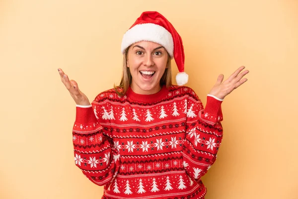 年轻的高加索女人在黄色背景下孤立地庆祝圣诞节 她得到了一个愉快的惊喜 兴奋地举起双手 — 图库照片