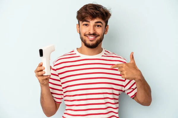 Joven Hombre Raza Mixta Sosteniendo Termómetro Aislado Sobre Fondo Azul —  Fotos de Stock