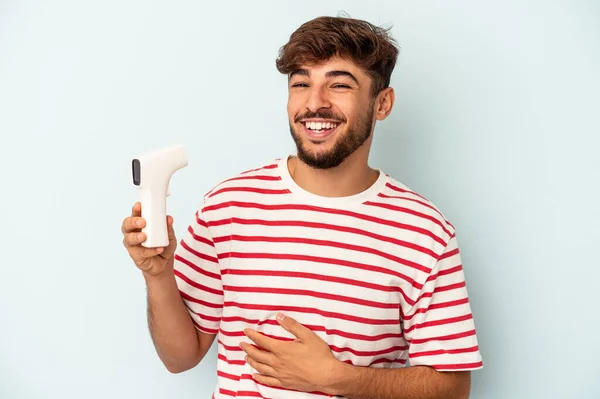 Joven Hombre Raza Mixta Sosteniendo Termómetro Aislado Sobre Fondo Azul —  Fotos de Stock