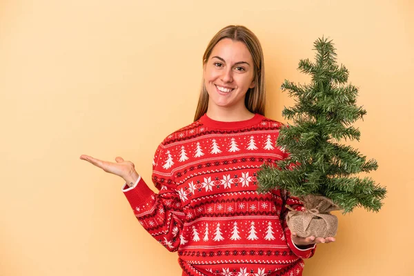 Mladá Běloška Drží Malý Vánoční Stromek Izolované Žlutém Pozadí Ukazující — Stock fotografie