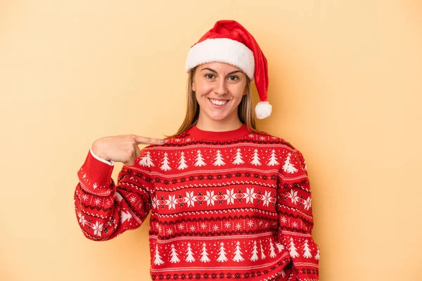 年轻的高加索女人用黄色背景的人来庆祝圣诞节 手拿着一件衬衫的复制品 自豪而自信 — 图库照片