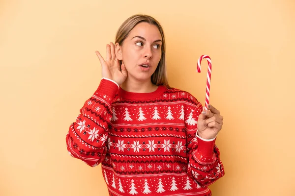 Mladá Běloška Drží Vánoční Hůl Izolované Žlutém Pozadí Snaží Poslouchat — Stock fotografie