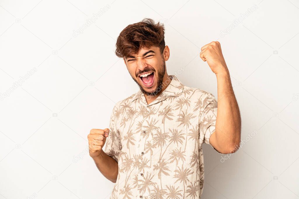 Young mixed race man isolated on grey background cheering carefree and excited. Victory concept.
