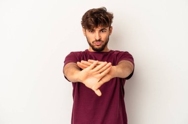 Genç melez adam gri arka planda izole edilmiş, elini uzatmış, dur işareti gösteriyor, bu da seni engelliyor..